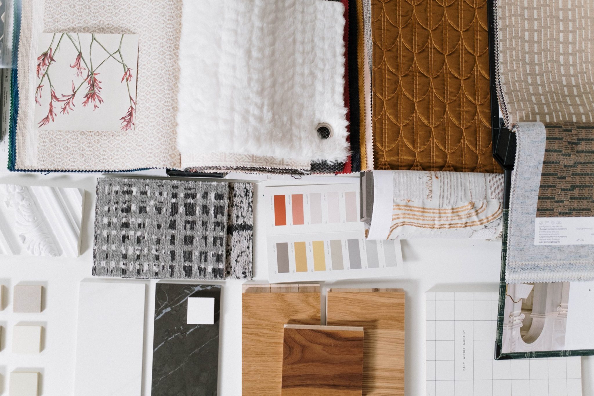 A flat-lay of interior material samples: textiles, stone, timber, and paint references.